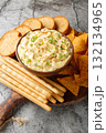Tasty Deviled Egg Dip with nachos, breadsticks, and toast close-up in a plate. Vertical 132134965