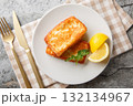 Saganaki is a very popular Greek appetizer of pan-seared cheese served alongside lemon wedges close-up in a plate. Horizontal top view 132134967