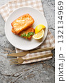 Light Greek appetizer Saganaki of fried cheese served with a lemon wedge close-up in a plate. Vertical top view 132134969