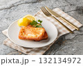 Saganaki is a very popular Greek appetizer of pan-seared cheese served alongside lemon wedges close-up in a plate. Horizontal 132134972