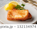 Saganaki is a Greek delicacy of fried cheese with a lemon wedge close-up in a plate. Horizontal 132134974