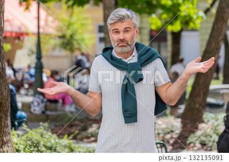 Confused mature man having doubts no idea being clueless uncertain feeling embarrassed, city street Confused mature man having doubts no idea being clueless uncertain feeling embarrassed, city street 132135091