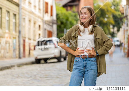 Caucasian young woman feeling sudden strong abdominal stomach ache, gastritis problem on city street 132135111