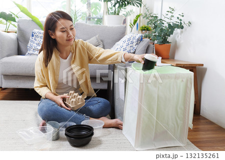Young Asian woman sorting recyclable waste at home, putting plastic containers and paper packaging into separate rubbish bin for recycling, eco sustainable living, environmental responsibility Young Asian woman sorting recyclable waste at home, putting plastic containers and paper packaging into separate rubbish bin for recycling, eco sustainable living, environmental responsibility 132135261