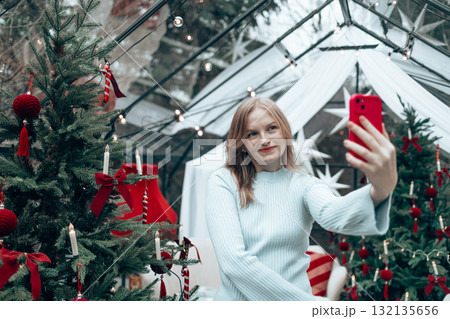 Smiling blonde woman taking Christmas selfie with smartphone 132135656