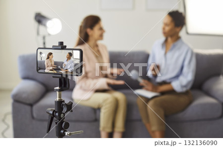 Smartphone camera on tripod framing two women in a candid interview scene Smartphone camera on tripod framing two women in a candid interview scene 132136090