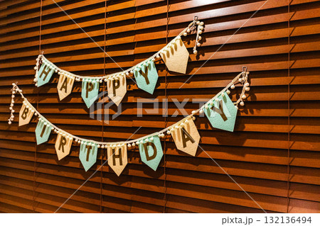 木製ブラインドに飾られたハッピーバースデーのガーランド 132136494