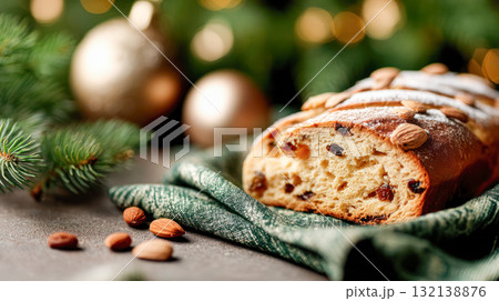 Freshly baked stollen bread with almonds and raisins, beautifully presented on a green cloth, surrounded by festive decorations and holiday ambiance Freshly baked stollen bread with almonds and raisins, beautifully presented on a green cloth, surrounded by festive decorations and holiday ambiance 132138876