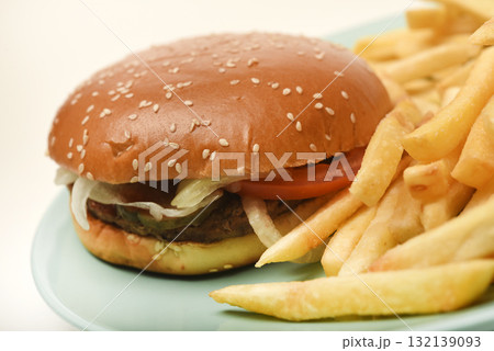 Hamburger with meat and vegetables and French fries. Fast food. Hamburger on a plate. Hamburger with meat and vegetables and French fries. Fast food. Hamburger on a plate. 132139093