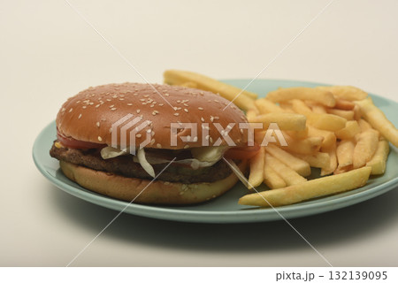 Hamburger with meat and vegetables and French fries. Fast food. Hamburger on a plate. 132139095