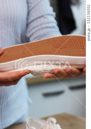 Woman checking the sole quality of white sneakers Sneakers with lace-up tops Woman checking the sole quality of white sneakers Sneakers with lace-up tops 132139201