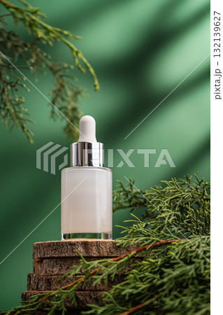 Glass cosmetic serum bottle on natural background with green leaves 132139627