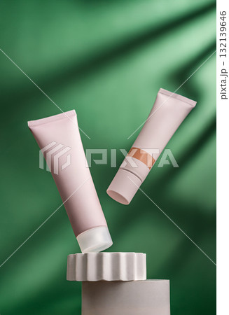 Two cosmetic tubes on pedestal with green background and soft lighting Two cosmetic tubes on pedestal with green background and soft lighting 132139646