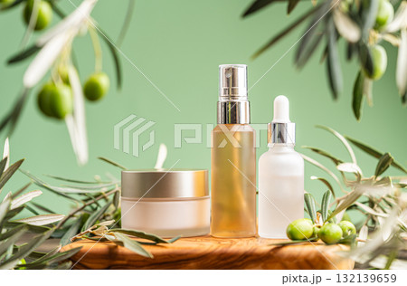Natural skincare products with olive branches on wooden surface and green background Natural skincare products with olive branches on wooden surface and green background 132139659