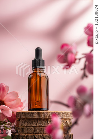 Glass serum bottle with dropper and pink flowers on wooden surface Glass serum bottle with dropper and pink flowers on wooden surface 132139674