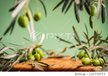 Fresh green olives and olive branches on wooden surface with green background 132139713