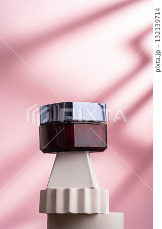 Elegant cosmetic jar on geometric pedestal with pink background 132139714