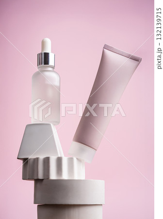 Facial serum and peeling mask on geometric display with pink background Facial serum and peeling mask on geometric display with pink background 132139715
