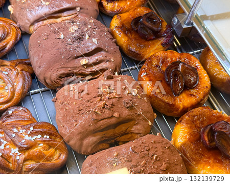 Pastries covered with chocolate and caramelized fruits on shelf. Confectionery art representing sweetness, texture, and bakery variety for indulgent taste. 132139729