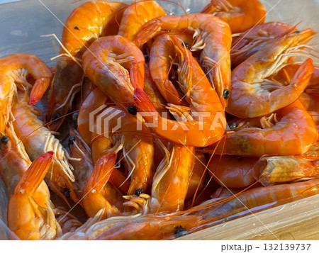 Boiled orange shrimps arranged inside a clear box. Freshness, seafood, and summer meal highlighting natural marine produce and culinary enjoyment. 132139737