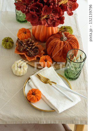 Thanksgiving table setting with decorative pumpkins, candles and string lights on white wooden table 132139796
