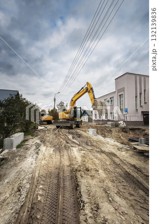 Construction site with heavy machinery operating on a cloudy day in a residential area Construction site with heavy machinery operating on a cloudy day in a residential area 132139836