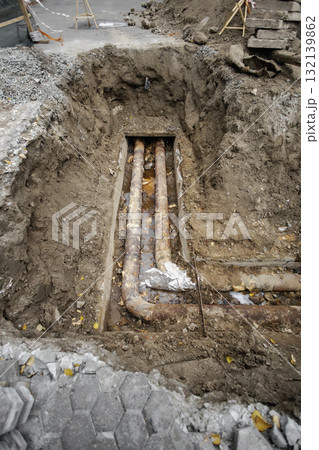 Construction site with exposed underground pipes being repaired in a city street during autumn 132139862