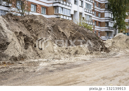 Construction site showing dirt pile near residential buildings during daytime work hours 132139913