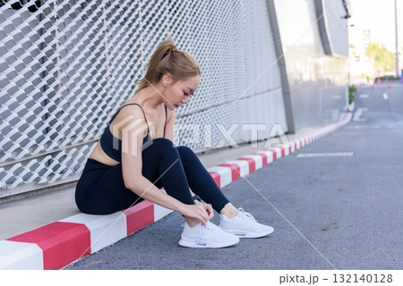 Exercise sport woman adjusts running shoe for workout outdoor, people enjoy preparing body for healthy fitness, stretching before or after vigorous exercise session. 132140128