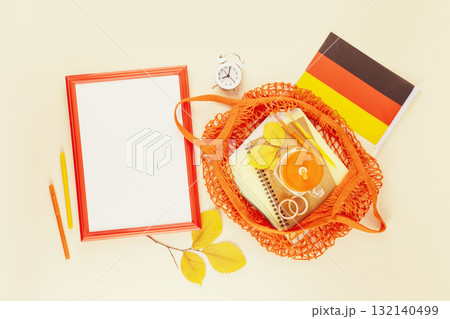 Back to school in Germany. School supplies in a bright yellow textile bag, frame and Germany flag on a light background with autumn leaves and copy space. Education in Germany. School sale concept Back to school in Germany. School supplies in a bright yellow textile bag, frame and Germany flag on a light background with autumn leaves and copy space. Education in Germany. School sale concept 132140499