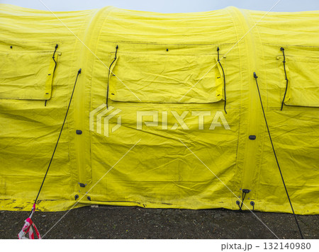 Worn yellow tarp with closed window covers at overcast day, full-frame close view 132140980