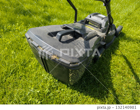 Lawnmower mowing green grass on a sunny day outdoors Lawnmower mowing green grass on a sunny day outdoors 132140981