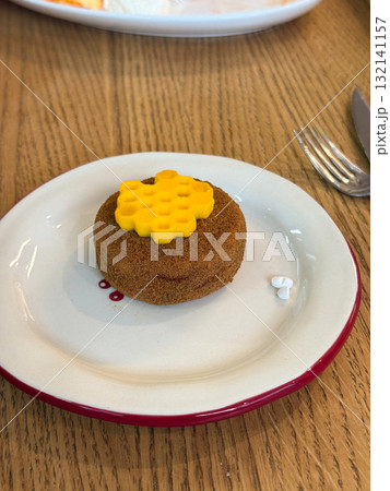 Round dessert with honeycomb decoration placed on white plate. Sweet bakery item presenting texture, craft, and culinary detail. 132141157