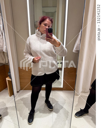 Close-up of woman adjusting jacket in fitting room. Exploration of texture, self-awareness, and identity through tactile perception of fashion and minimalist elegance. 132141252