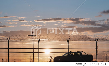 Airport security patrol driving along perimeter fence at sunset Airport security patrol driving along perimeter fence at sunset 132141521