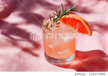 Refreshing Cocktail With Grapefruit and Rosemary on a Pink Tablecloth in Sunny Outdoor Setting Refreshing Cocktail With Grapefruit and Rosemary on a Pink Tablecloth in Sunny Outdoor Setting 132141900