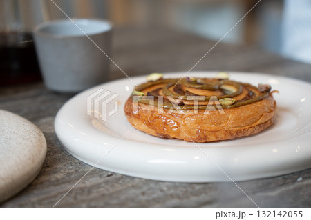Fresh pistachio pastry served on a white plate with a cup of black coffee in a modern cafe Fresh pistachio pastry served on a white plate with a cup of black coffee in a modern cafe 132142055