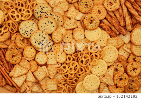 Colorful mix of salty crackers varieties: sticks and pretzels, triangular and round. Snacks food background 132142192