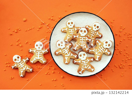 Healthy Halloween fun skeleton cookies on orange background. Party spooky sweet snacks for kids Healthy Halloween fun skeleton cookies on orange background. Party spooky sweet snacks for kids 132142214
