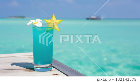 Blue tropical mocktail cocktail on a wooden pier with a beautiful turquoise ocean background 132142379