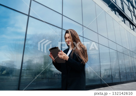 Young Woman Using Tablet Outside Modern Building With Reflective Glass During Daytime in an Urban Environment Young Woman Using Tablet Outside Modern Building With Reflective Glass During Daytime in an Urban Environment 132142610