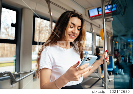 Young woman enjoying smartphone while traveling on public transport, smiling and relaxed, modern urban setting, technology lifestyle concept Young woman enjoying smartphone while traveling on public transport, smiling and relaxed, modern urban setting, technology lifestyle concept 132142680