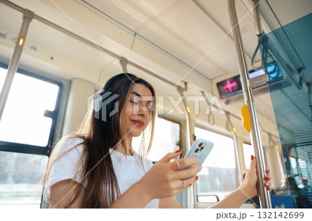 Young woman enjoying music on smartphone while commuting in public transport with headphones, urban lifestyle concept Young woman enjoying music on smartphone while commuting in public transport with headphones, urban lifestyle concept 132142699