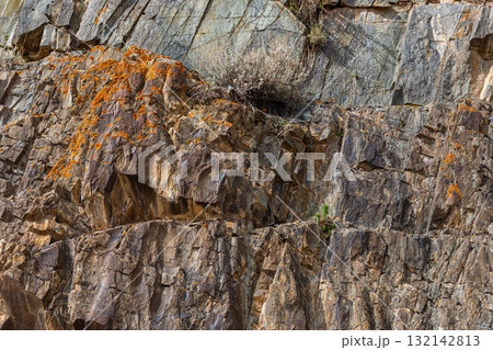 Rugged rock formation with orange lichen in mountainous Kyrgyzstan region Rugged rock formation with orange lichen in mountainous Kyrgyzstan region 132142813
