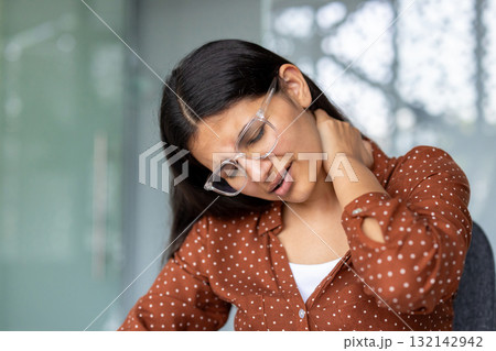 Young businesswoman suffering from neck pain, touching and massaging her painful neck with hand, tired from computer work, feeling exhausted, suffering from office syndrome Young businesswoman suffering from neck pain, touching and massaging her painful neck with hand, tired from computer work, feeling exhausted, suffering from office syndrome 132142942