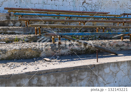 Dilapidated wooden benches in decaying outdoor stadium 132143221