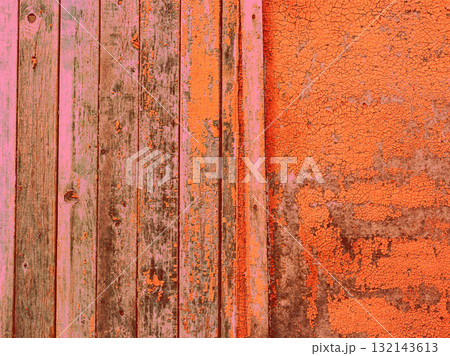 Weathered wood and peeling paint texture in shades of orange and pink. This abstract image features a close-up of aged wood planks and cracked paint, creating a unique visual texture. 132143613