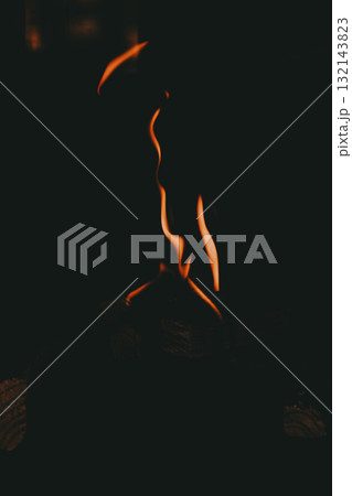 Dark minimalistic shot of orange flames rising in the darkness, abstract fire shapes dancing above burning wood 132143823