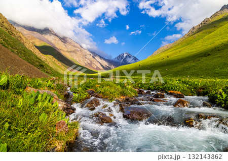 Serene mountain valley with flowing river and green vegetation in Kyrgyzstan 132143862