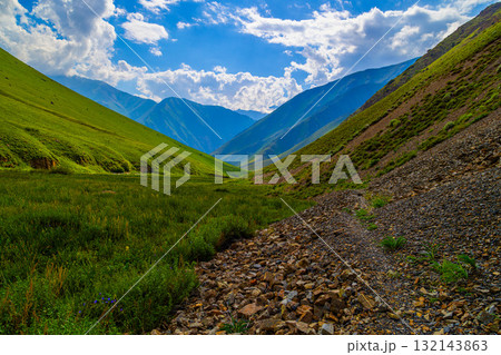 Majestic mountain landscape with grassy fields and rocky path in Kyrgyzstan 132143863